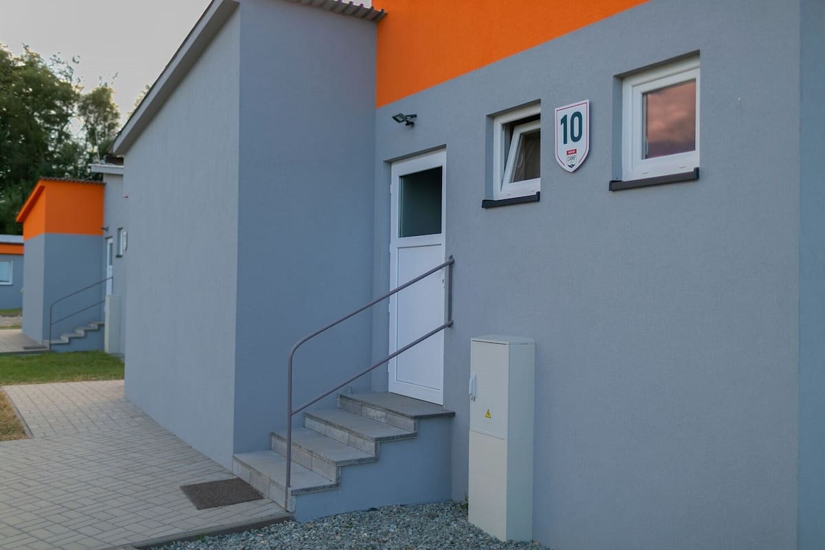 A building with a blue and orange exterior, a white door, and a small window with the number 10.