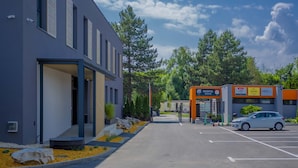 A modern building with a reception area, a parking lot, and a small adjacent structure with signage. - Hotel & Restaurant Resort Barca  - Campsite (Kosice)