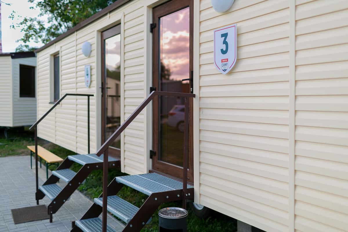 A row of mobile homes with a number sign on the door, a bench, and steps leading to the entrance.