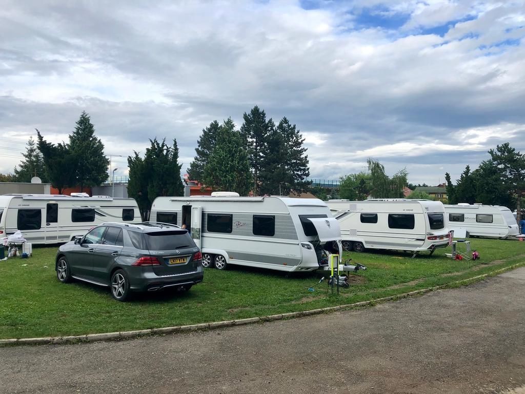 Parque para caravanas con varias caravanas y un coche estacionado sobre el césped.