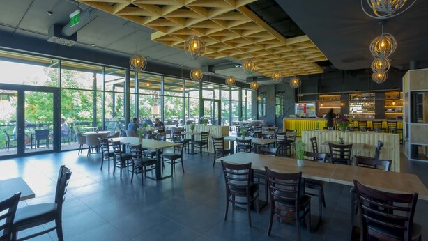 A spacious restaurant with large windows, wooden ceiling, and modern pendant lighting. - Hotel & Restaurant Resort Barca  - Campsite (Kosice)