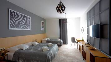 A modern hotel room with two beds, a desk, a chair, and a TV.
