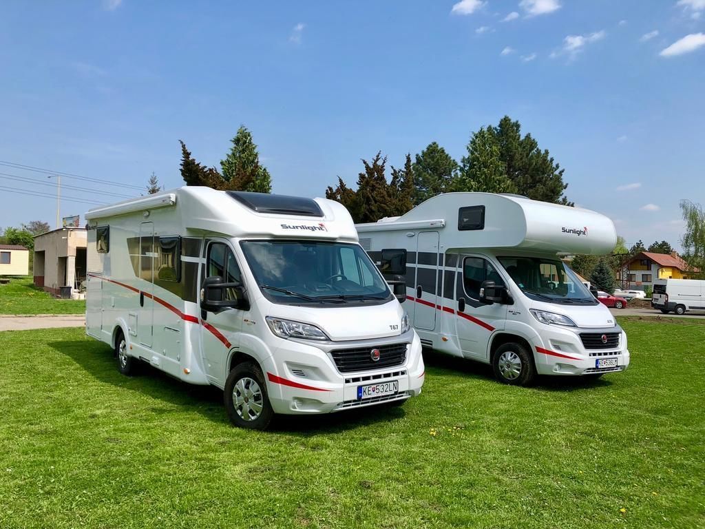 Two Sunlight RVs parked on a grassy field with a clear sky.