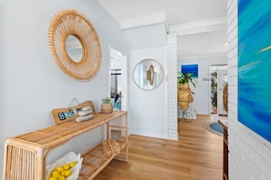 Ein modernes Interieur mit einer Holzbank, zwei Wandspiegeln und einem Korbstuhl.