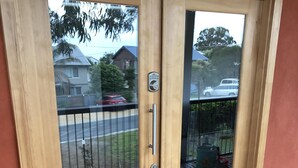 Una puerta de madera con un panel de vidrio, un teclado de bloqueo y un picaporte.