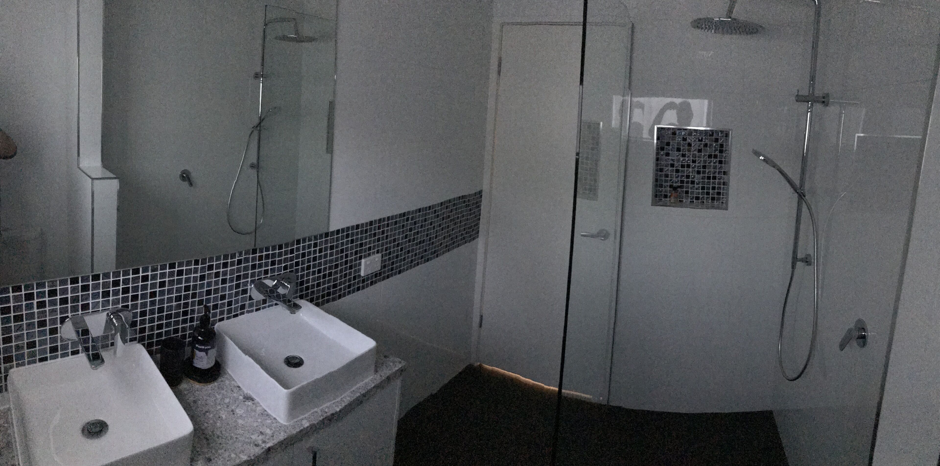 A bathroom with a white sink, a mirror, and a shower area.