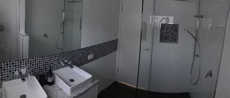 A bathroom with a white sink, a mirror, and a shower area.