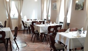 A dining area with multiple tables and chairs, arranged in a spacious layout with large windows allowing natural light. - Hotel Restaurant Stern (Mannheim)
