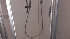 Een douchecabine met glazen wanden, een handdouche en een douchekop.