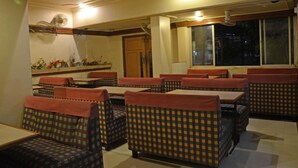 Un espace repas avec des banquettes et des tables à carreaux, une porte en bois et une fenêtre donnant sur l’extérieur.
