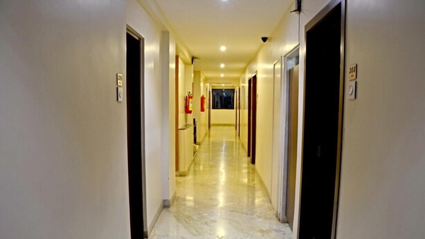 Un couloir d’hôtel avec un sol en marbre, des portes des deux côtés et des panneaux indiquant les sorties de secours.