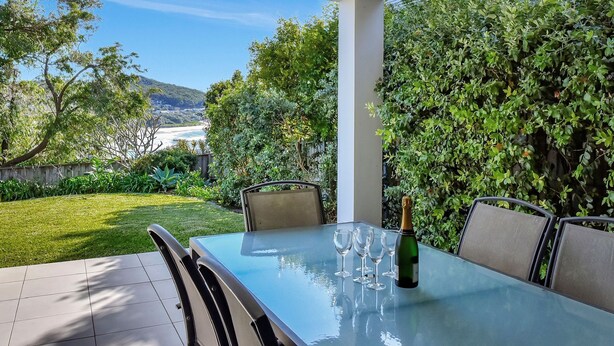 Eine Außenpatio mit Glastisch, Stühlen und einer Champagnerflasche.