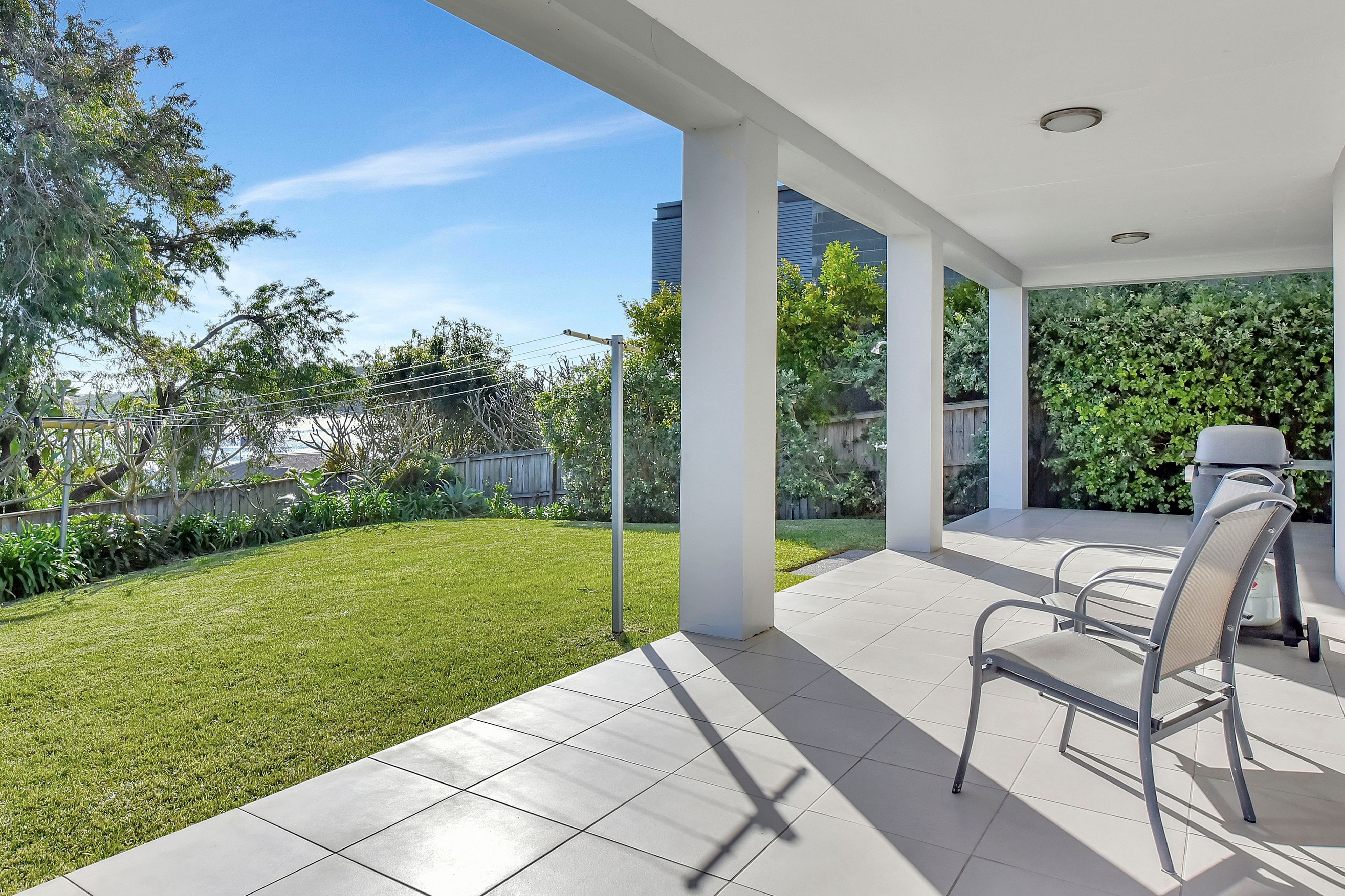 A covered patio area with a view of a well-maintained lawn and trees.
