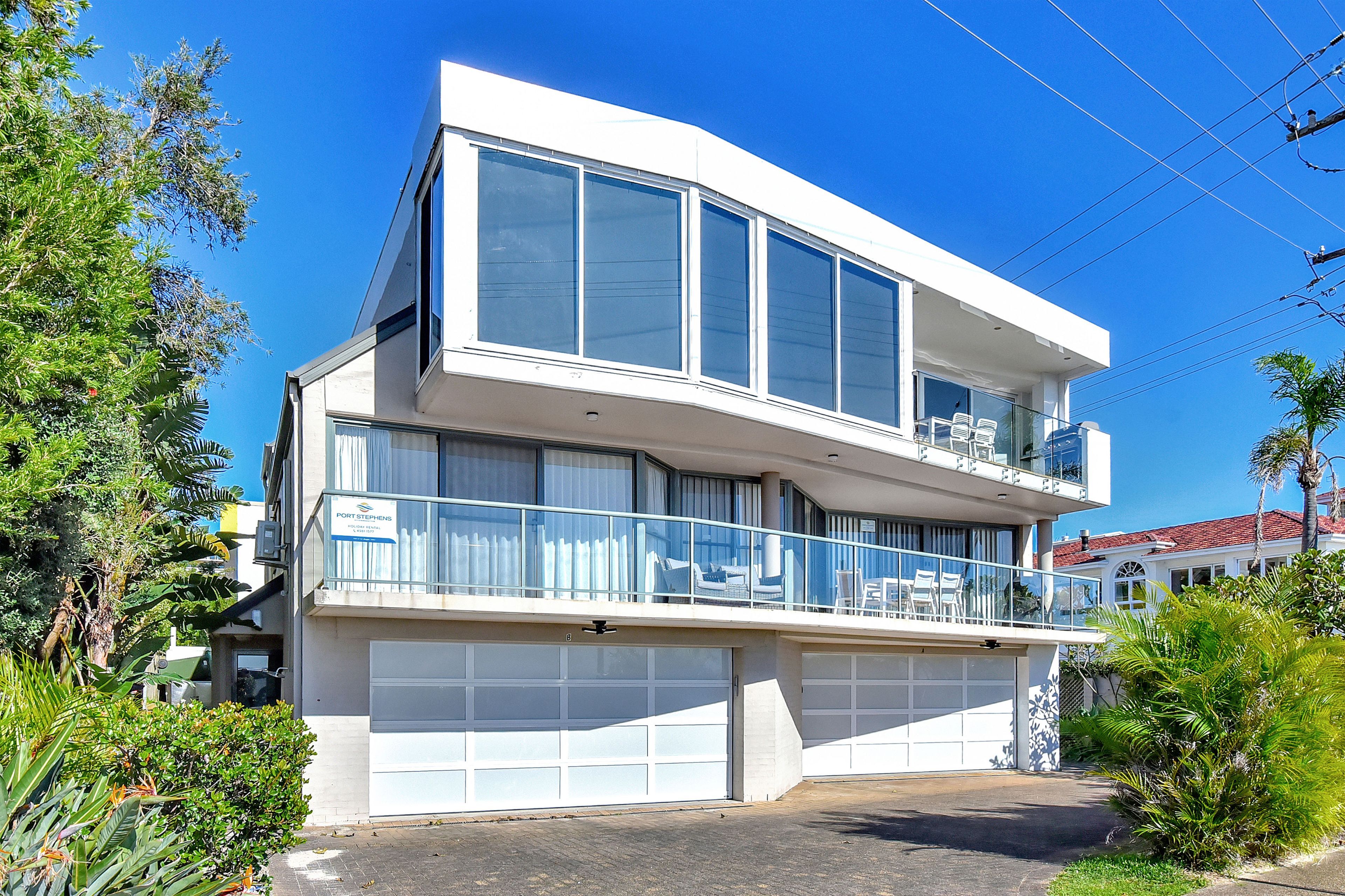 A two-story building with a balcony, large windows, and a garage.