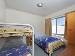 A room with bunk beds, a window with curtains, and a ceiling light. - Bella Vista 3 Shoal Bay Apartment with Water Views (Shoal Bay)