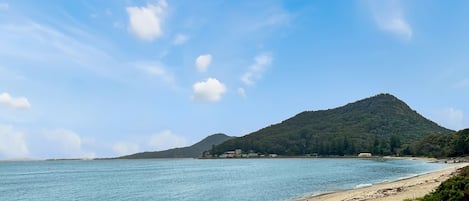 A beach with a mountain in the background and clear skies.