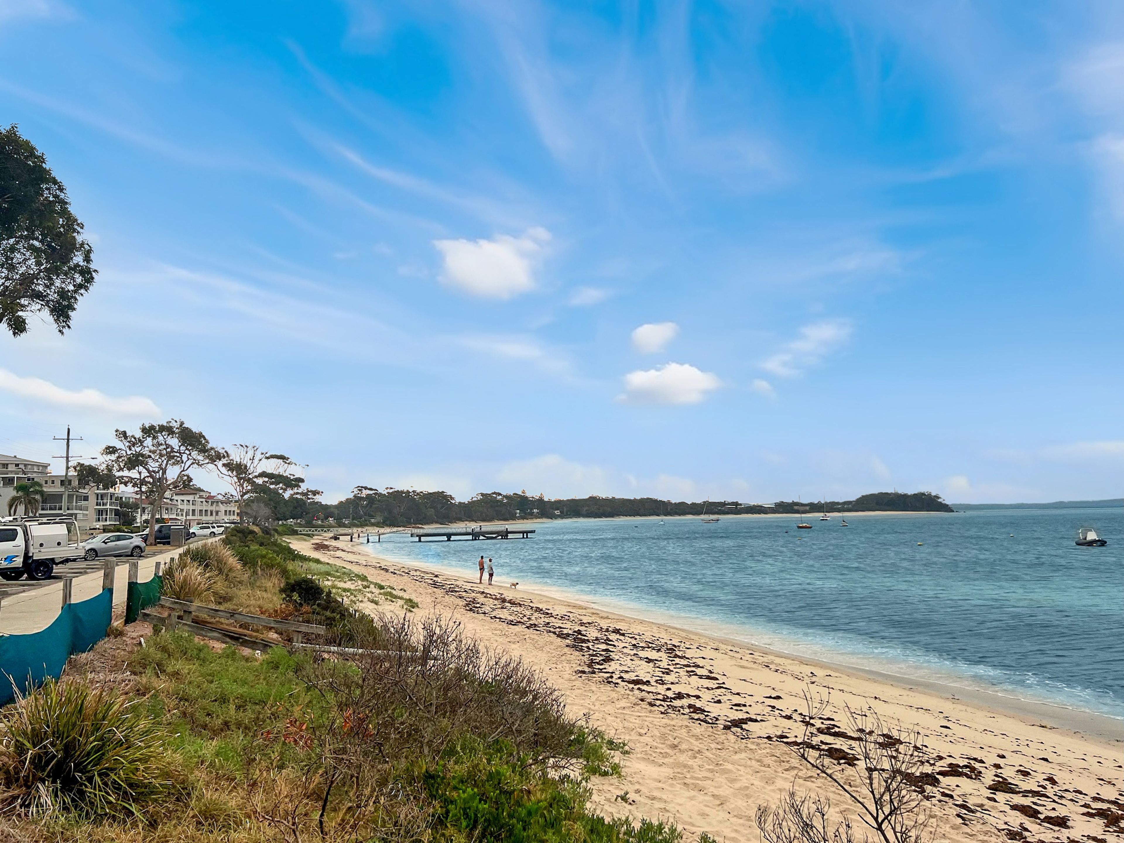 A beach with a clear sky, a sandy shore, and a calm sea.