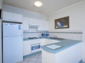 A kitchen with white cabinets, a microwave, a stove, and a sink.