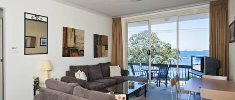 Una sala de estar amoblada con un conjunto de sofá, una mesa de centro y un televisor sobre un mueble.