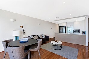 A modern living room with a dining area, a sofa, a coffee table, and a lamp. - The Shoal 510 panoramic water views (Shoal Bay)