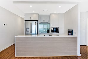 A modern kitchen with stainless steel appliances, a central island, and a view to the outdoors. - The Shoal 510 panoramic water views (Shoal Bay)