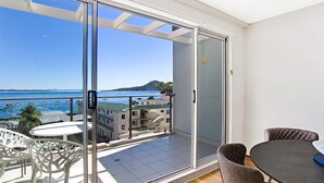 A balcony with a view of the sea and a mountain, furnished with a table and chairs. - The Shoal 510 panoramic water views (Shoal Bay)