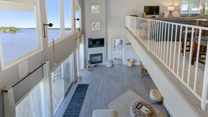 Un vaste espace de vie doté d’une cheminée, de grandes fenêtres donnant sur un plan d’eau et d’un balcon avec une balustrade.