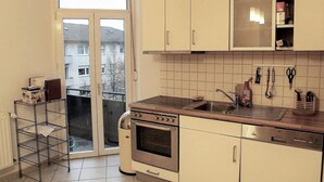 Eine kleine Küche mit Backofen, Spüle und Fenster mit Blick auf eine Wohngegend.
