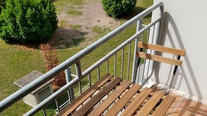 Ein Balkon mit einer hölzernen Bank und einem Metallgeländer.