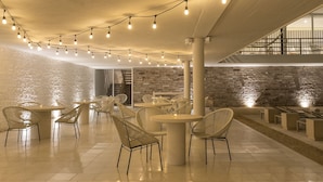 A spacious indoor area with tables and chairs, string lights, and a brick wall. - Hotel Boutique Casa Lulu (Mazatlán)