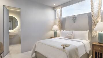 A modern bedroom with a large bed, bedside lamps, a mirror, and a decorative wall piece.