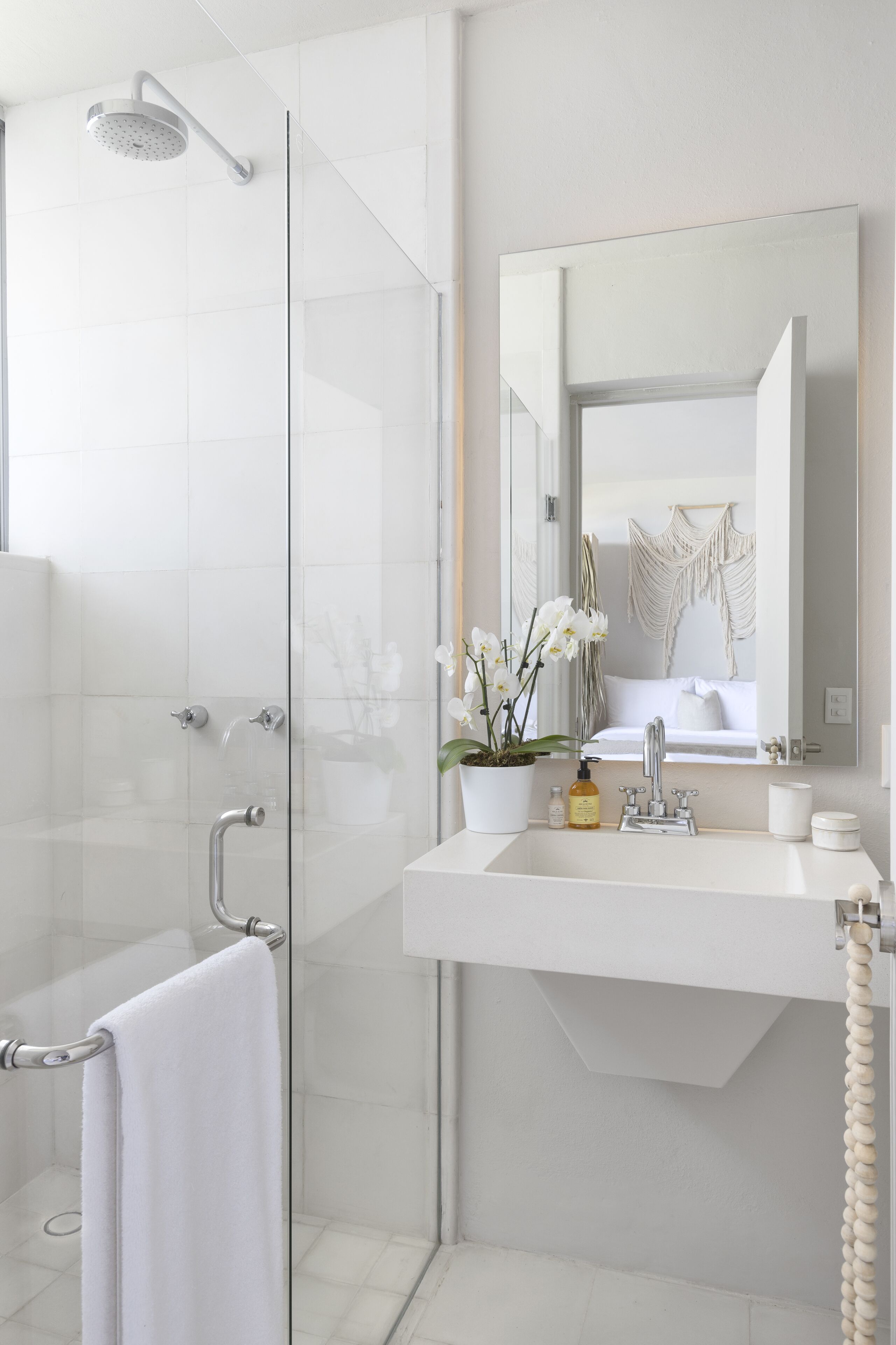 A modern bathroom with a glass shower enclosure, a white sink with a mirror above it, and a towel rack.