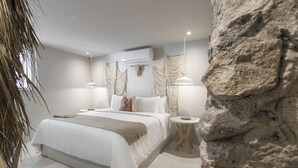 A modern bedroom with a large bed, a round side table, and a decorative wall piece. - Hotel Boutique Casa Lulu (Mazatlán)