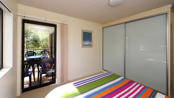 Un dormitorio con una cama, una puerta corredera a un balcón y un cuadro en la pared.
