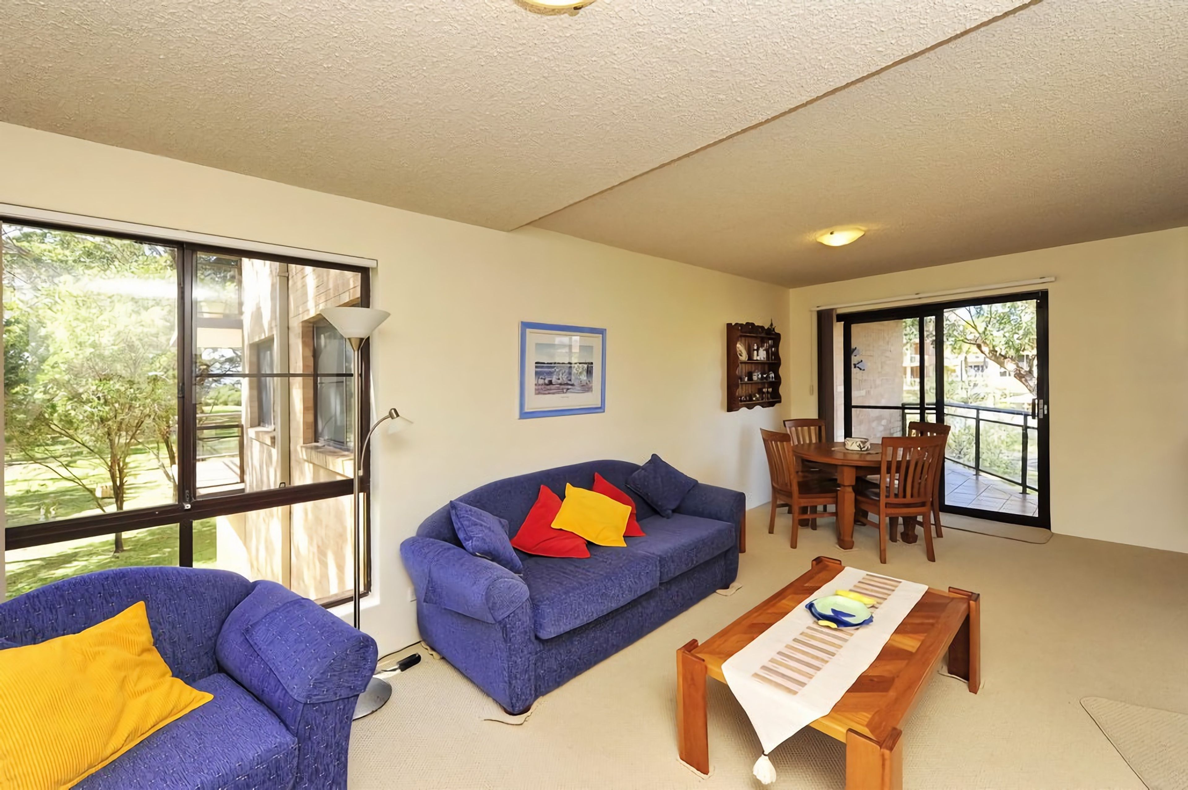 A living room with a blue sofa, a wooden coffee table, and a dining area with a table and chairs.
