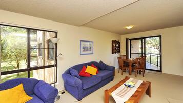 A living room with a blue sofa, a wooden coffee table, and a dining area with a table and chairs.