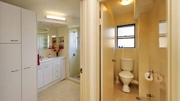 A bathroom with a toilet, a shower, and a sink.