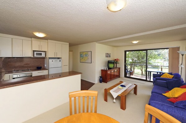 A compact living space with a kitchenette, a dining area, and a seating area with a view.