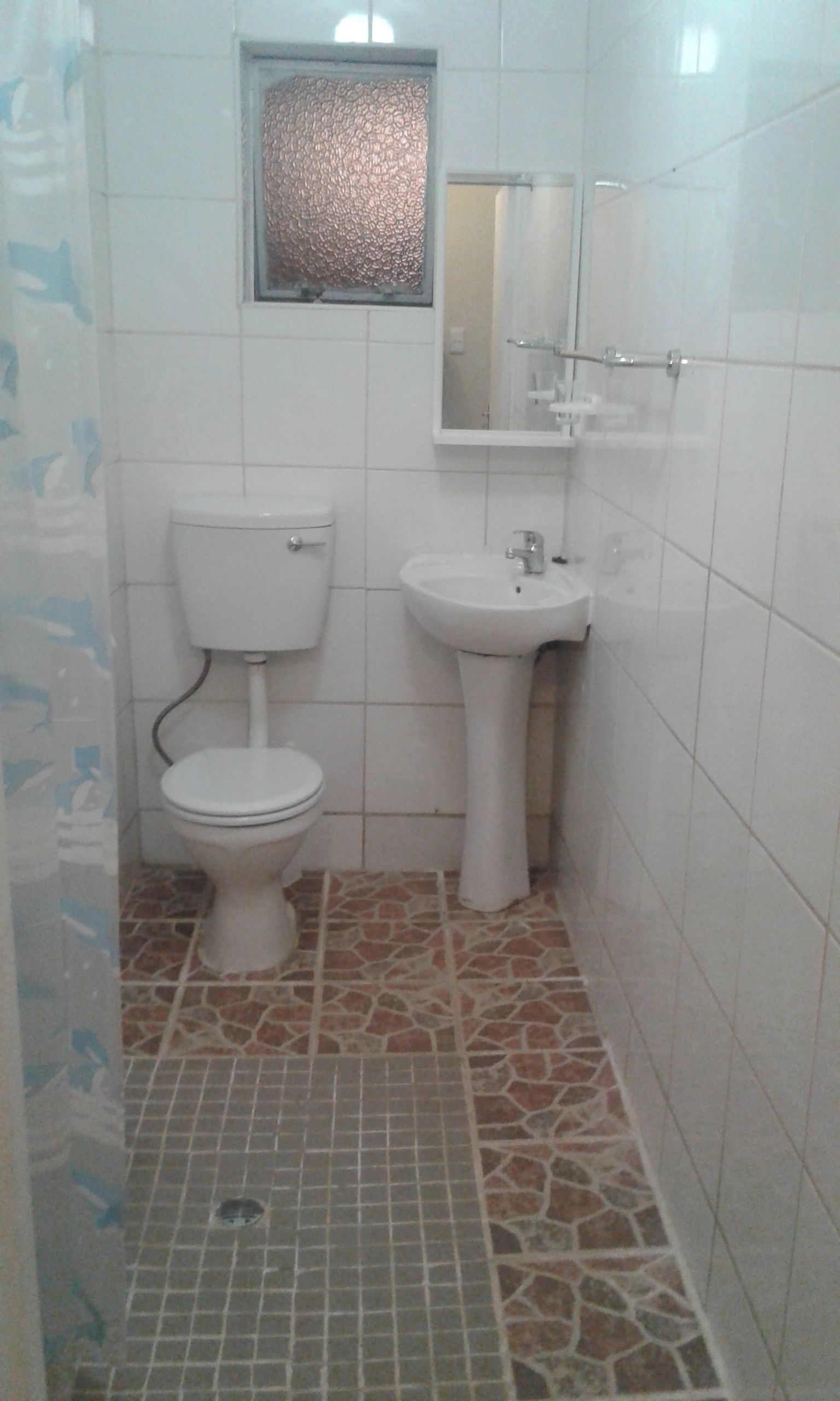 A small bathroom with a toilet, sink, and tiled floor.