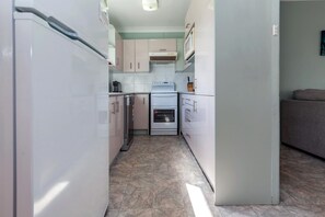 A compact kitchen with white appliances, a microwave, and a stove.