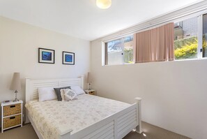 Una camera da letto con un letto, due comodini, una finestra con tende e due quadri appesi al muro.