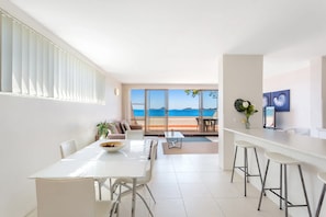 Un interno moderno con zona pranzo, cucina e un balcone vista mare.