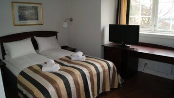 Une chambre d’hôtel avec un lit, un bureau, une télévision et une fenêtre.
