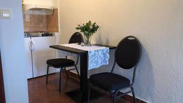 Een kleine keuken met een eettafel, twee stoelen en een vaas met bloemen.
