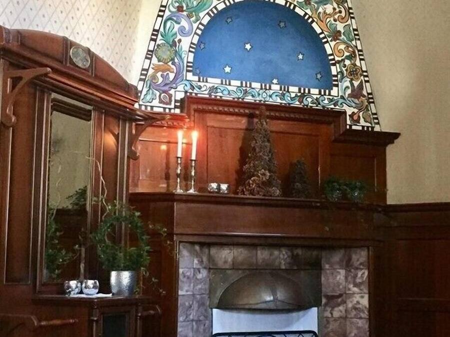 A traditional fireplace with a decorative tile surround, a wooden mantelpiece, and a mirror cabinet to the left.