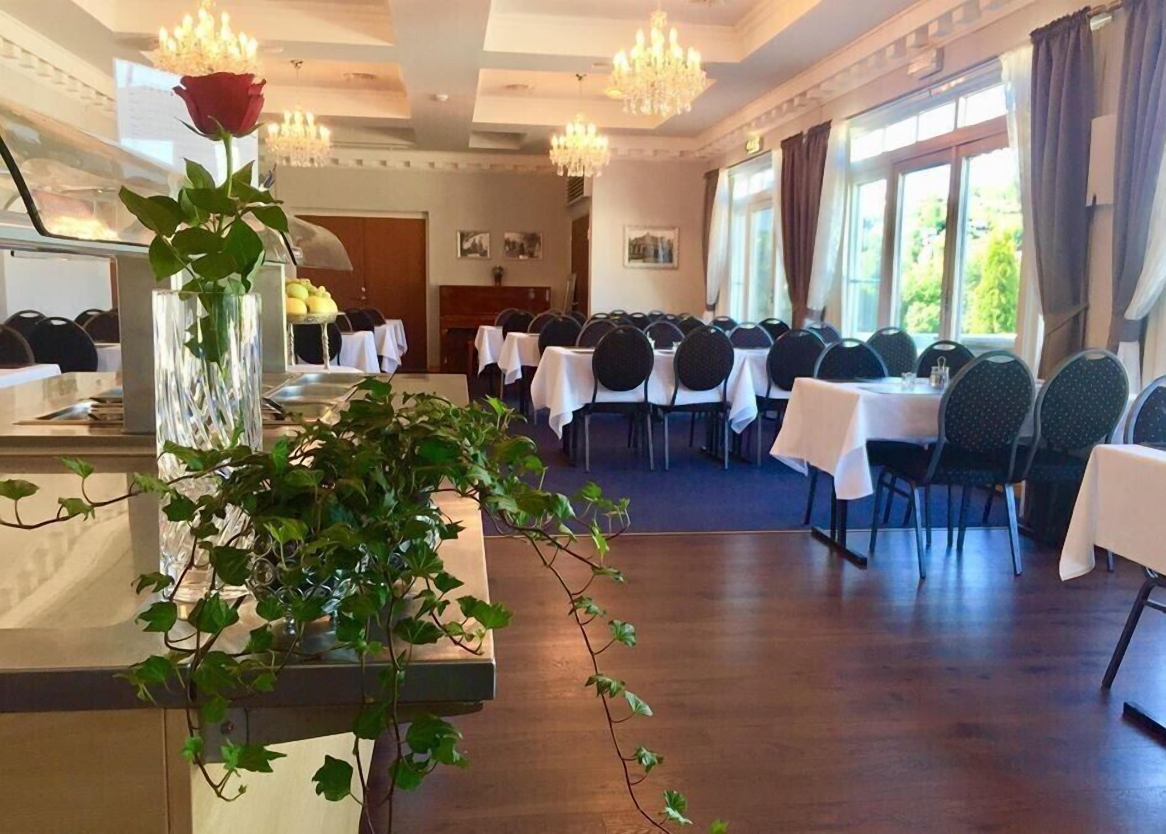 A dining area with round tables, chairs, and a long counter with a vase of flowers.