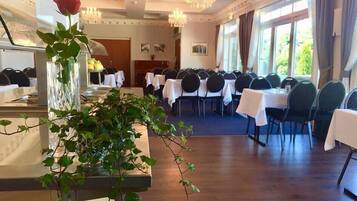 A dining area with round tables, chairs, and a long counter with a vase of flowers.