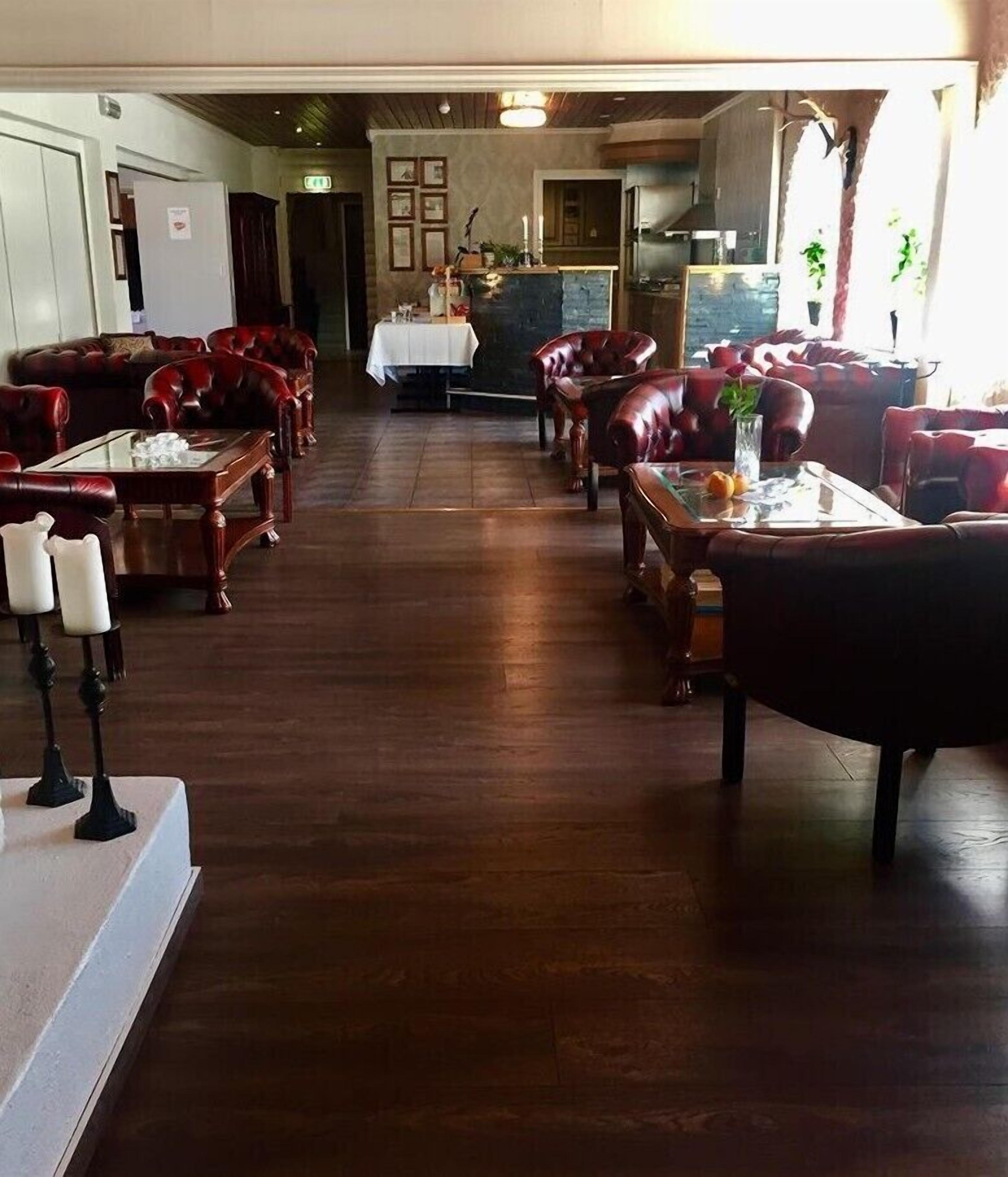 Un amplio vestíbulo de hotel con un largo suelo de madera, asientos de cuero y una mesa central con mantel blanco.