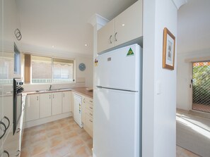 Eine Küche mit weißen Schränken, einem eingebauten Backofen und einem Kühlschrank.