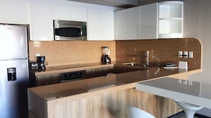 A modern kitchen with a stainless steel refrigerator, a built-in microwave, a coffee maker, and a sink.